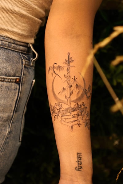 A fine line black and grey tattoo on the forearm featuring a sword with floral elements and geometric accents — by gloria.shi.ink, los angeles