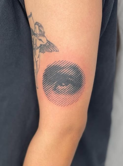 A minimalist black and grey linework tattoo of an angel on the upper arm, featuring simple lines and subtle shading — by Level tattoo, los angeles