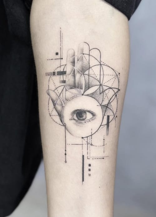 A black and grey geometric tattoo on the forearm featuring an eye surrounded by intricate dotwork and sacred geometry patterns — by Jian Liang, los angeles