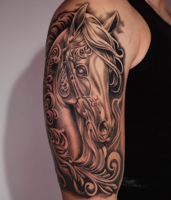 A detailed black and grey horse tattoo on the upper arm with ornate patterns and realistic shading — by Johnny Ayala, fontana, ca