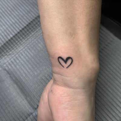 A minimalist blackwork heart tattoo on the wrist — by Maddie Ramirez, los angeles