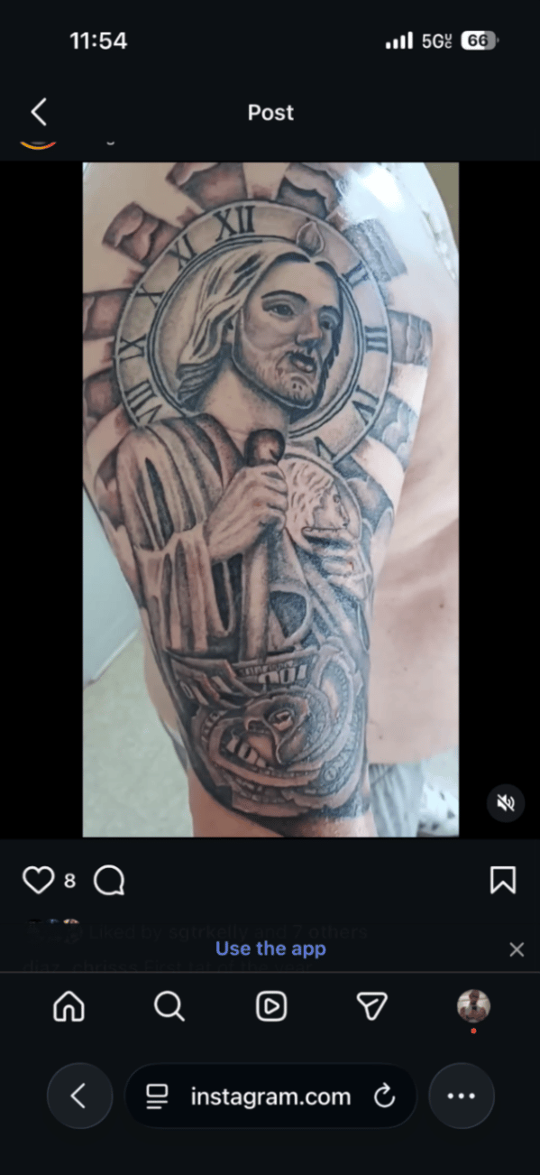 A black and grey realism tattoo of Jesus Christ holding a staff, with a clock halo, on the upper arm. The piece features detailed shading and religious symbolism — by christopher diaz, los angeles