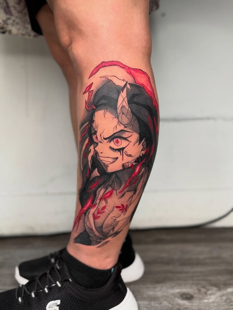 graphic anime tattoo of nezuko from demon slayer in black, grey and red down the calf by zealous, an anime tattoo artist in the arts district, los angeles