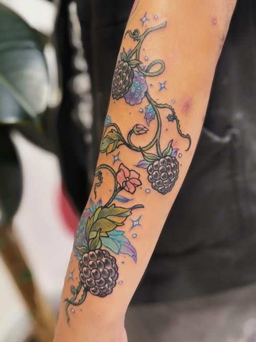 A colorful neo-traditional tattoo on the forearm featuring blackberries and floral elements with illustrative details — by Tweetwee, los angeles