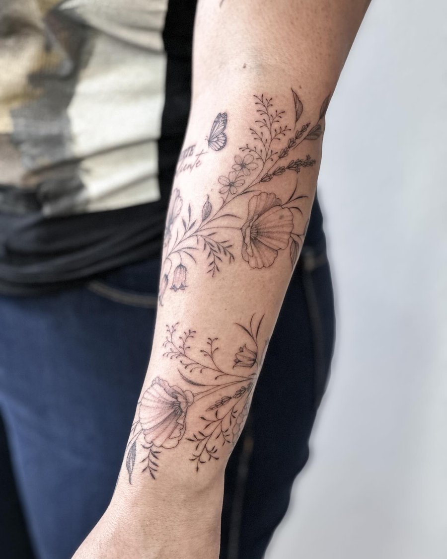 A delicate black and grey fine line floral tattoo with a butterfly on the forearm, featuring intricate botanical details — by Melanie Benoit, los angeles