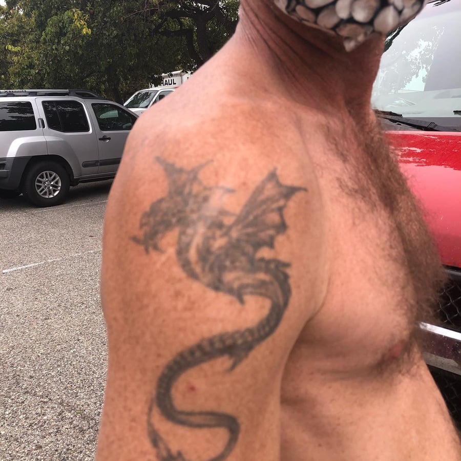 A bold black and grey dragon tattoo on the shoulder, featuring tribal and blackwork styles — by Sandra Price, los angeles