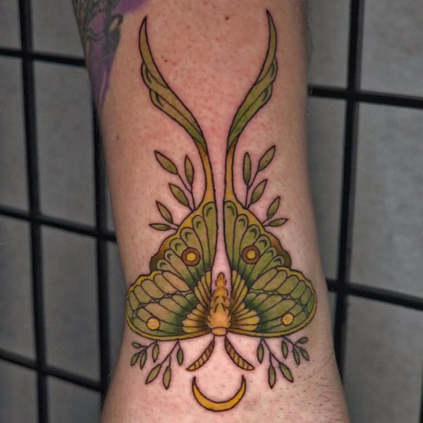 A colorful neo-traditional moth tattoo on the forearm, featuring a crescent moon and ornate details — by Miguel ANGELO, temecula, ca