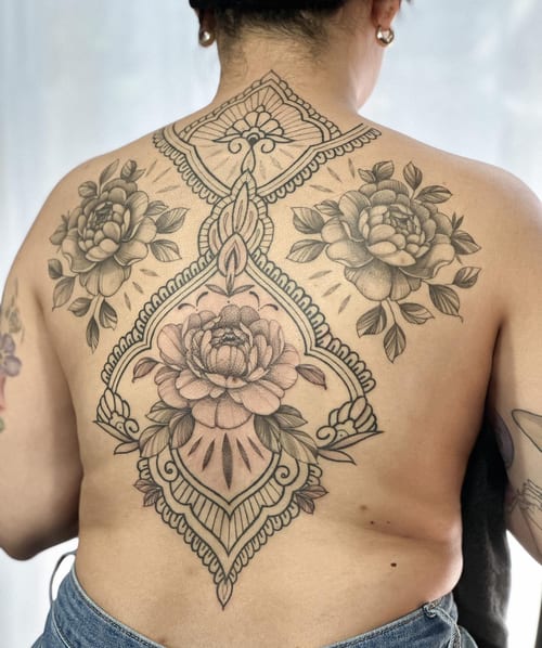 An intricate black and grey floral mandala tattoo on the back, featuring detailed ornamental patterns and roses — by Melanie Benoit, los angeles