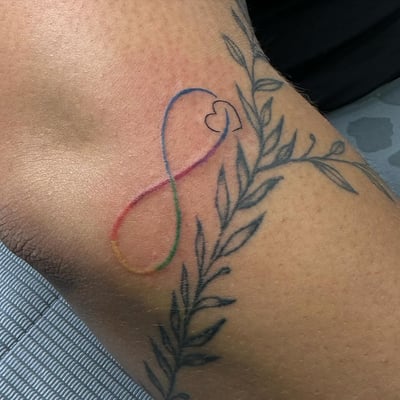 A delicate infinity symbol with a heart and leaves in rainbow colors on the arm — by Maddie Ramirez, los angeles