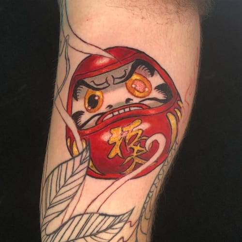 A colorful Japanese daruma doll tattoo on the forearm with bold lines and vibrant colors — by Sandra Price, los angeles