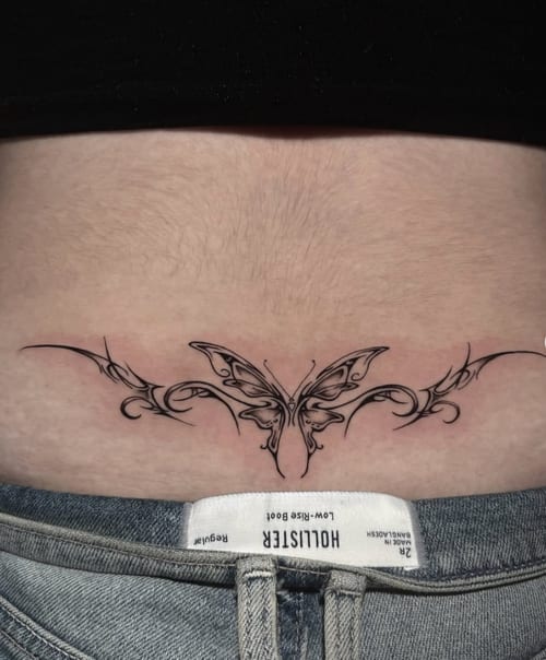 A fine line ornamental butterfly tattoo on the stomach, featuring intricate black and grey linework — by Shelby Bianco, los angeles