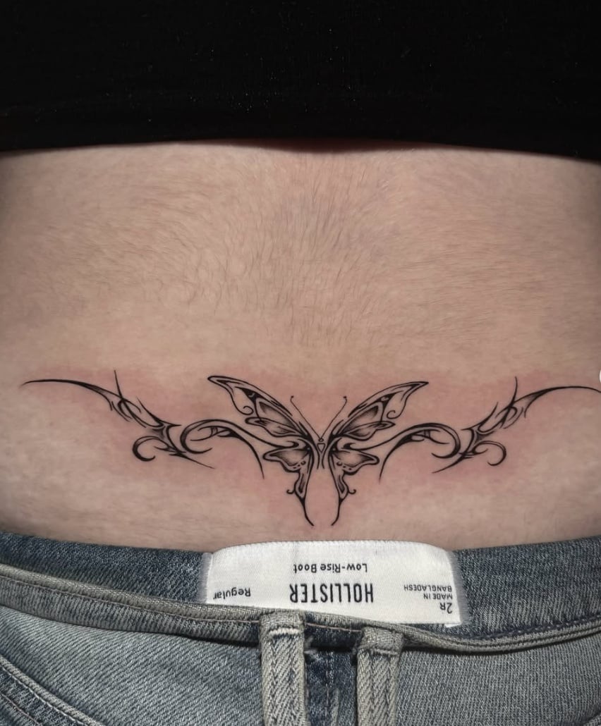 A fine line ornamental butterfly tattoo on the stomach, featuring intricate black and grey linework — by Shelby Bianco, los angeles