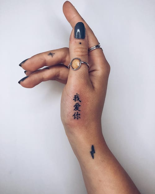 A minimalist black ink Chinese script tattoo on the hand, featuring simple and clean lettering — by Level tattoo, los angeles