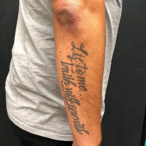 A bold black script lettering tattoo on the forearm featuring a quote — by Sandra Price, los angeles