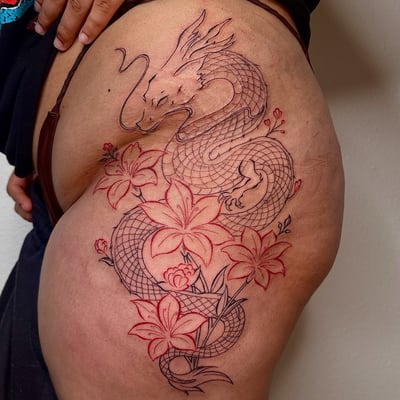 A Japanese-style dragon with flowers tattoo on the thigh, featuring intricate linework and a mixed color profile — by NJ TATTOOZ, los angeles