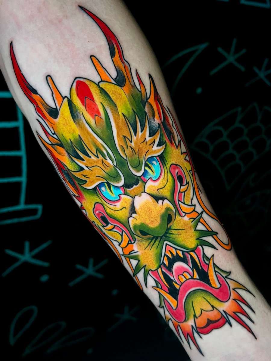 A vibrant color Japanese-style dragon tattoo on the forearm, featuring bold outlines and dynamic shading with bright oranges and greens — by Josue Bravo, los angeles