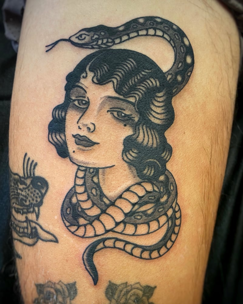 blackwork tattoo of a traditional woman's head with a snake coiling through her hair by Josh Rosa, a blackwork tattoo artist in highland park, los angeles