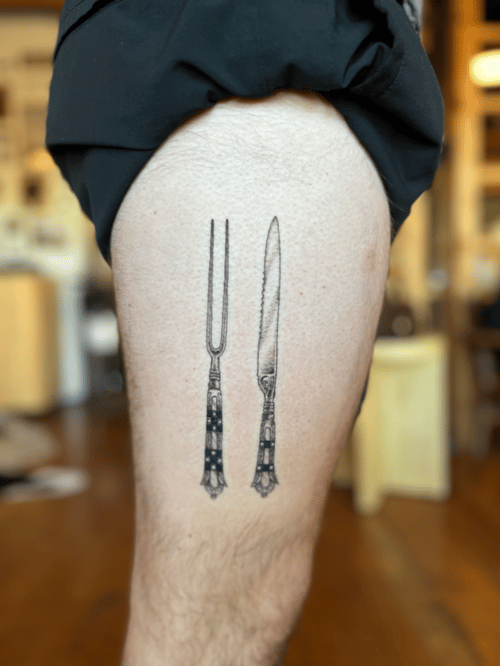 A minimalist black and grey tattoo of a fork and knife on the thigh, featuring clean lines and simple design — by Dylan Aiello, los angeles