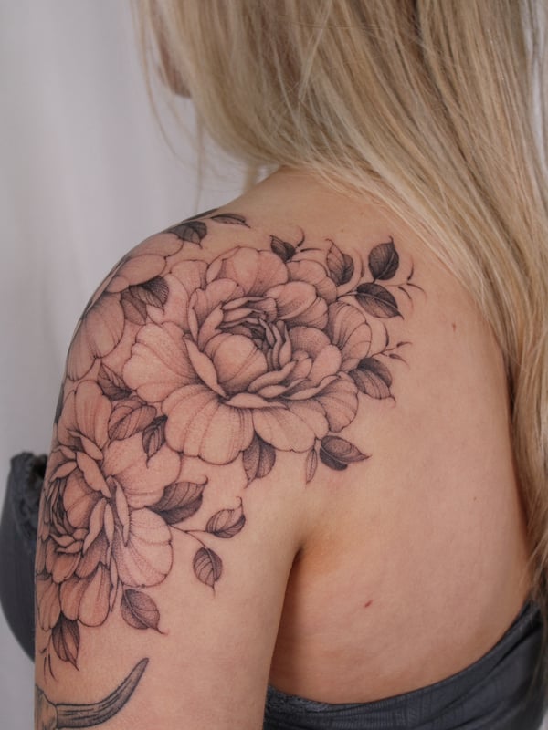 A delicate black and grey floral tattoo on the shoulder featuring detailed flowers and leaves — by Melanie Benoit, los angeles