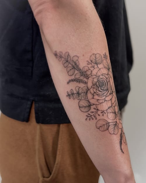 A delicate fine line floral tattoo on the forearm, featuring a black and grey flower arrangement with intricate details — by Melanie Benoit, los angeles