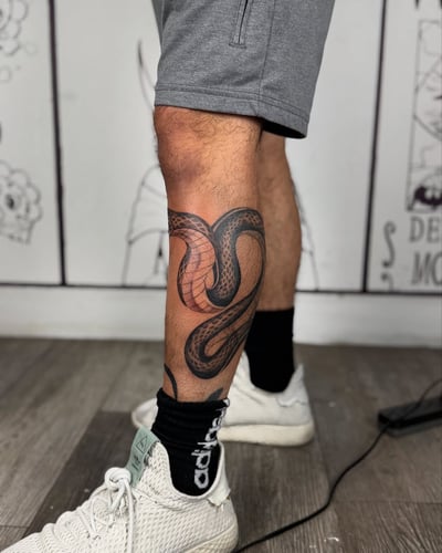 A bold blackwork snake tattoo wrapped around the calf with intricate scale details — by zealous, los angeles