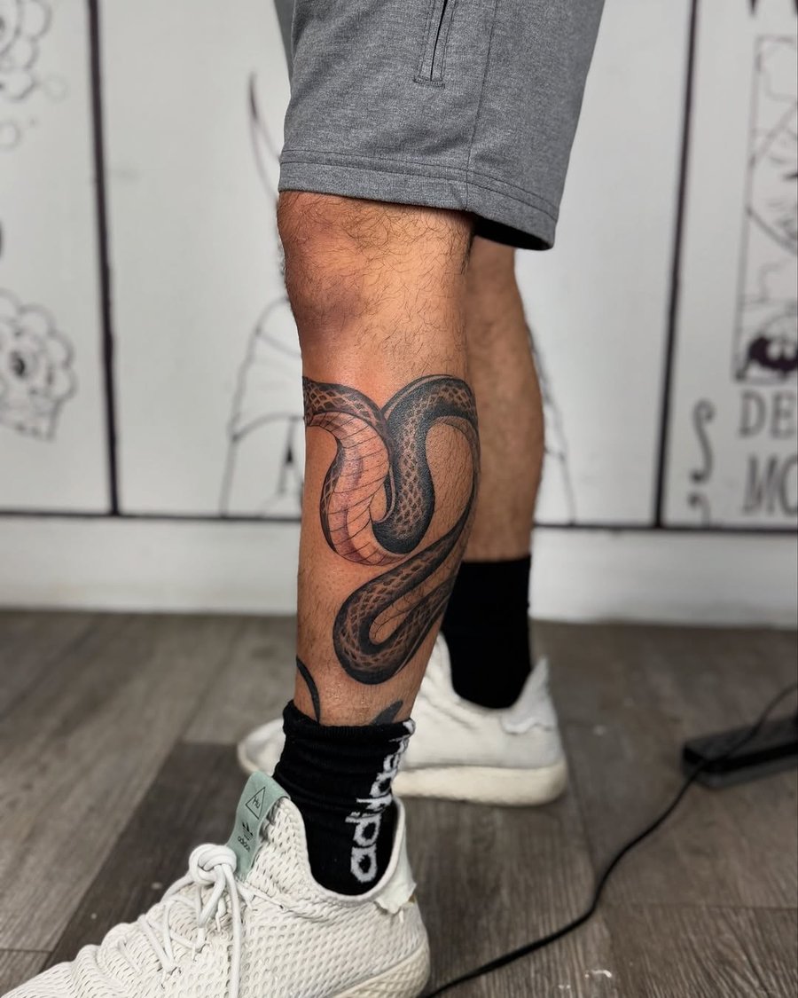 A bold blackwork snake tattoo wrapped around the calf with intricate scale details — by zealous, los angeles