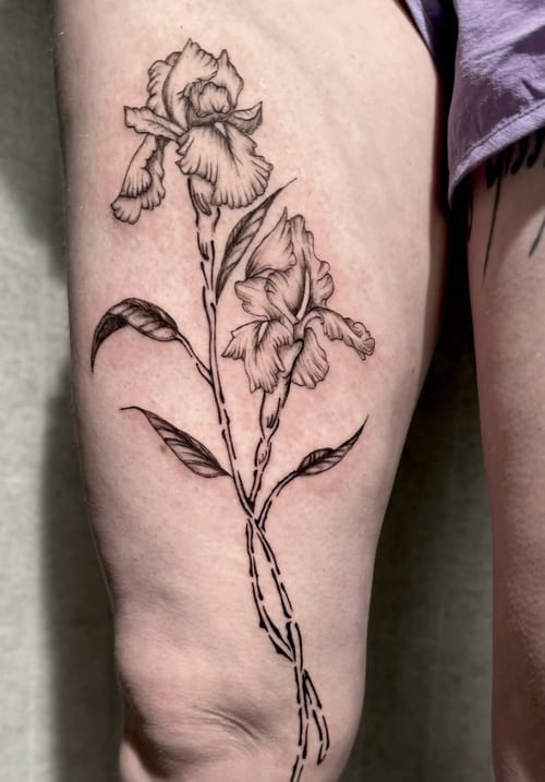 A fine line black and grey tattoo of two flowers with detailed petals and stems on the thigh — by Shelby Bianco, los angeles