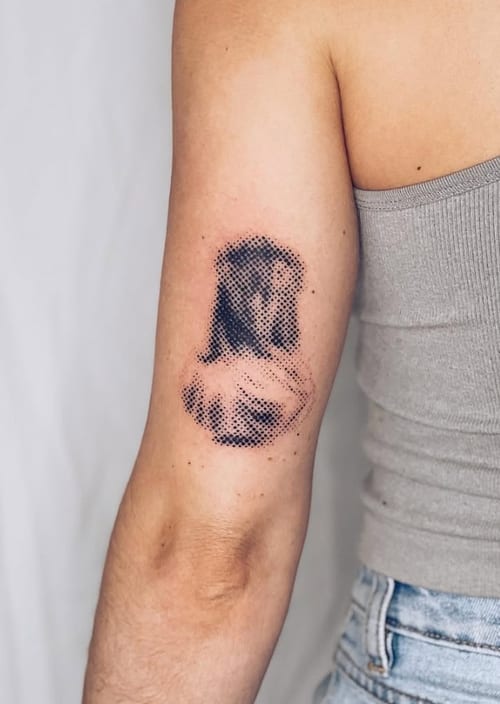 A black and grey dotwork portrait on the upper arm, featuring detailed shading and a textured appearance — by Level tattoo, los angeles