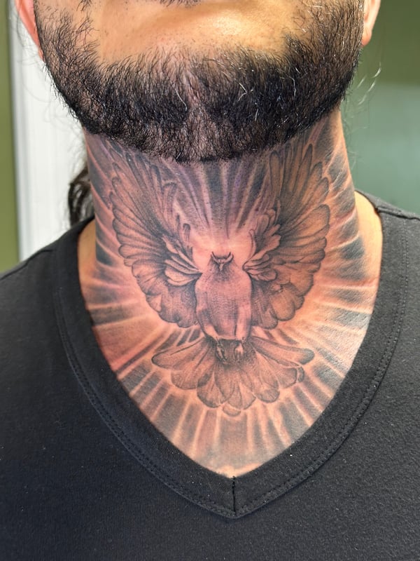 A black and grey realism tattoo of a bird with outstretched wings on the neck, featuring detailed shading and texture — by Humilde tattoos, los angeles