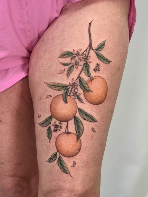 A delicate illustrative tattoo of oranges on a branch with flowers on the thigh, featuring a clean and colorful botanical style — by Melanie Benoit, los angeles
