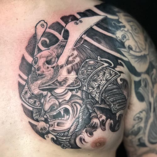 A bold black and grey samurai mask tattoo on the chest, featuring intricate details and a skull element — by Sandra Price, los angeles