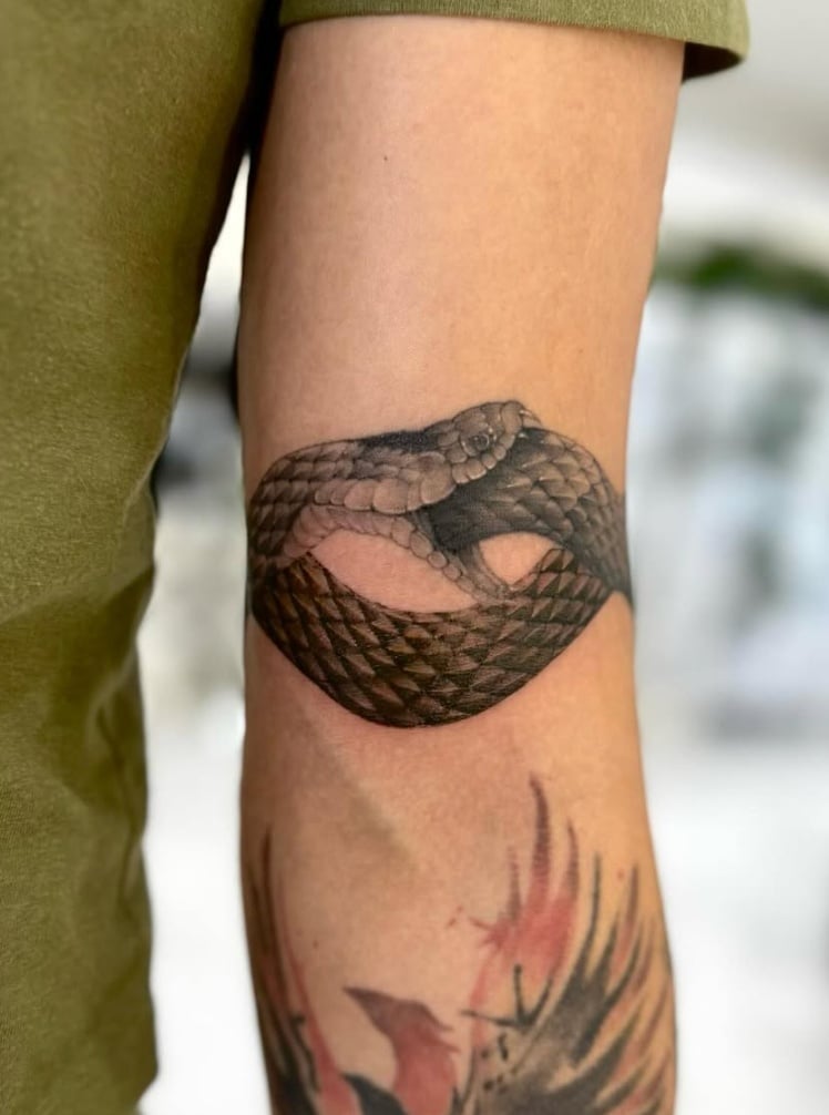 A realistic black and grey tattoo of a snake coiled around the forearm with detailed scales and shading — by otaybeatdown, los angeles