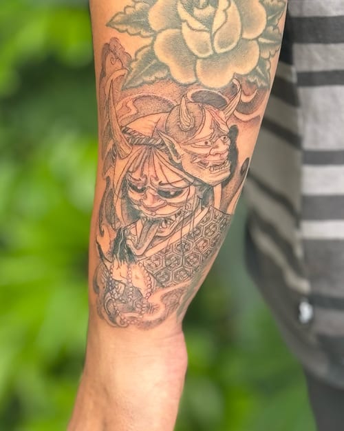 A detailed black and grey hannya mask tattoo on the forearm, featuring intricate Japanese design elements — by Sandra Price, los angeles