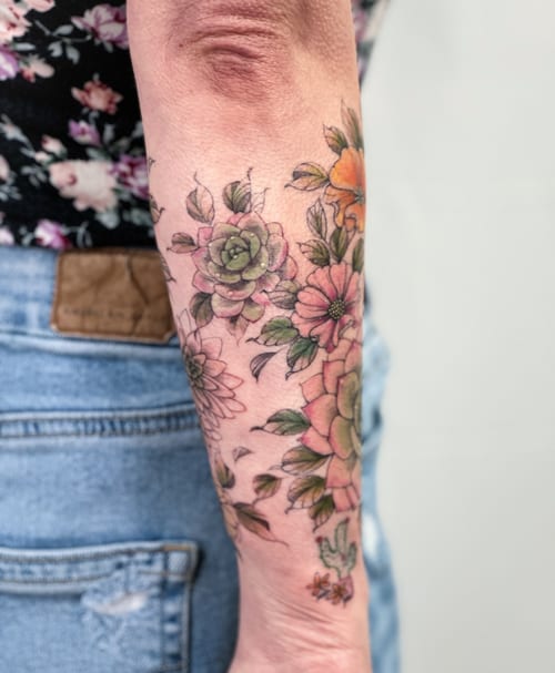 A colorful floral arrangement tattoo on the forearm with a delicate watercolor style — by Melanie Benoit, los angeles