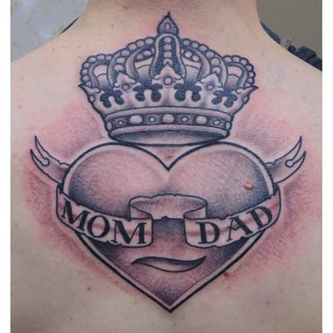 A bold black and grey heart tattoo on the back with a crown and 'Mom Dad' banner — by Samuel Connelly, san diego, ca