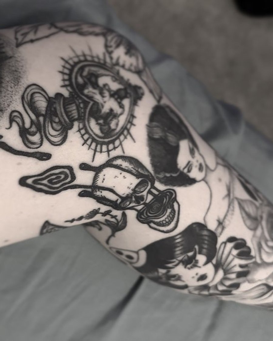 A black and grey tattoo featuring a skull and woman's face in a dark, ornate style — by Maddie Ramirez, los angeles