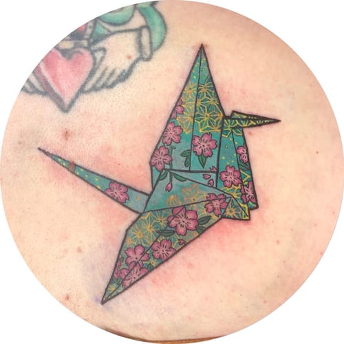 A colorful origami crane tattoo with floral patterns in a Japanese style — by Sandra Price, los angeles