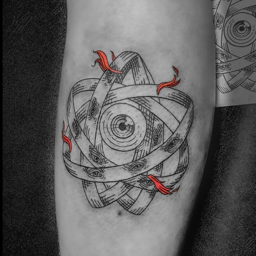 A surreal blackwork tattoo on the forearm featuring an intricate design of eyes within a circular pattern, accented with red flames — by Tag Devilish, los angeles