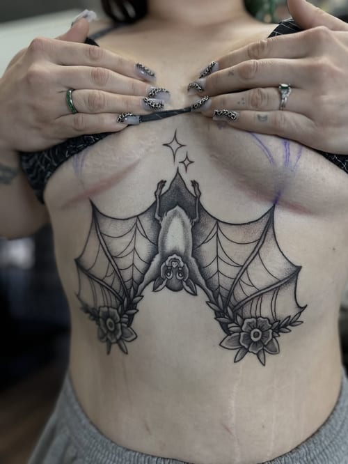 A black and grey fine line bat with floral details on the sternum — by Maddie Ramirez, los angeles