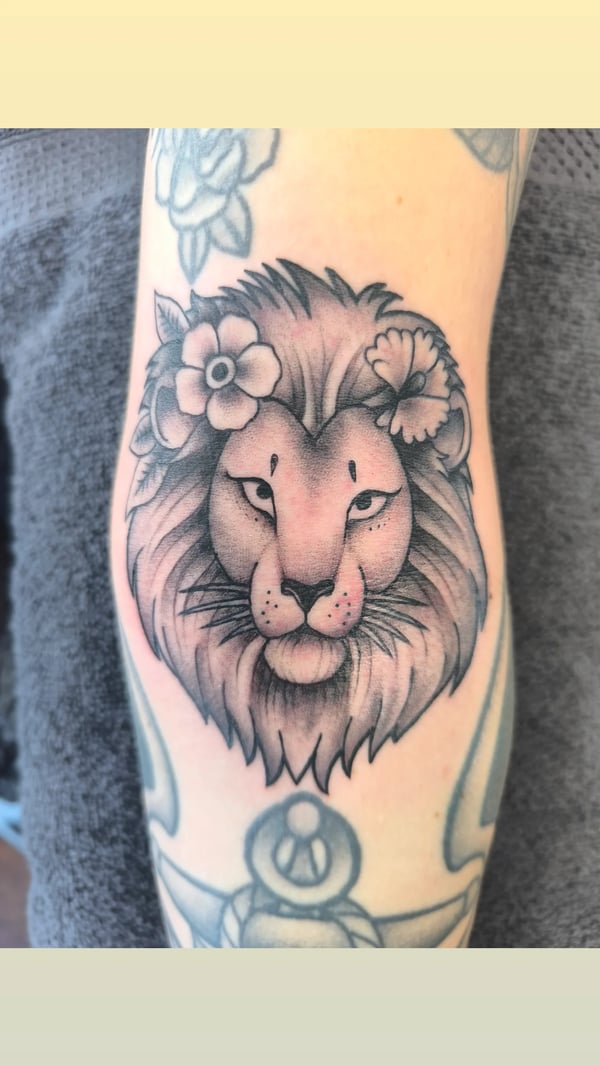 A bold black and grey neo-traditional lion with flowers on the forearm — by Samuel Connelly, san diego, ca