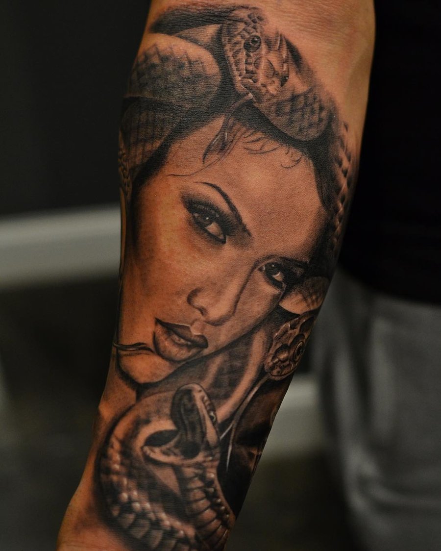 A black and grey realistic tattoo of Medusa with snakes on the forearm, showcasing detailed shading and lifelike features — by Johnny Ayala, los angeles