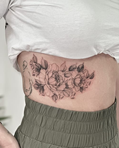 A delicate black and grey floral bouquet tattoo on the rib, featuring fine line work and clean shading — by Melanie Benoit, los angeles
