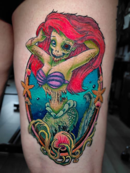 A colorful Neo-Traditional tattoo of a zombie mermaid with skeletal features on the thigh, featuring vibrant hues and dark art elements — by anoetic.designs.ultd, los angeles