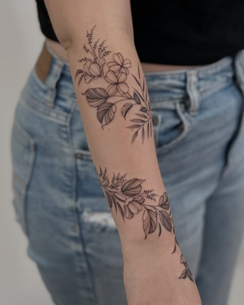 A delicate black and grey floral arrangement tattoo on the forearm, featuring fine line work and minimalistic design — by Melanie Benoit, los angeles