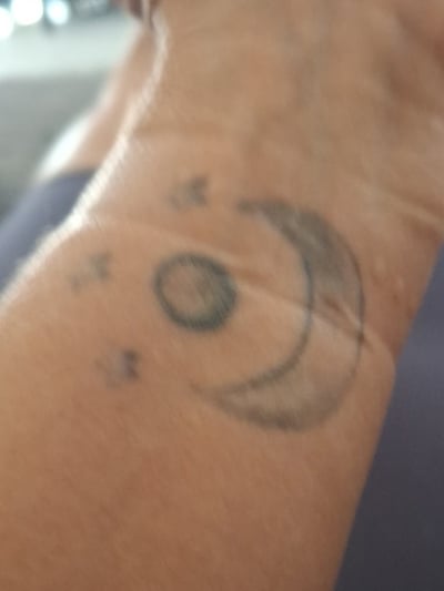 A simple black and grey crescent moon and stars tattoo on the wrist, done in a minimalist style — by Kiera Garvin, los angeles