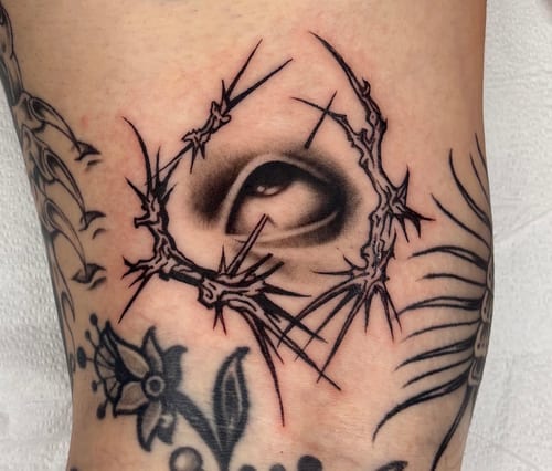 A black and grey tattoo of a realistic eye surrounded by abstract blackwork lines on the leg — by velvet devil, los angeles