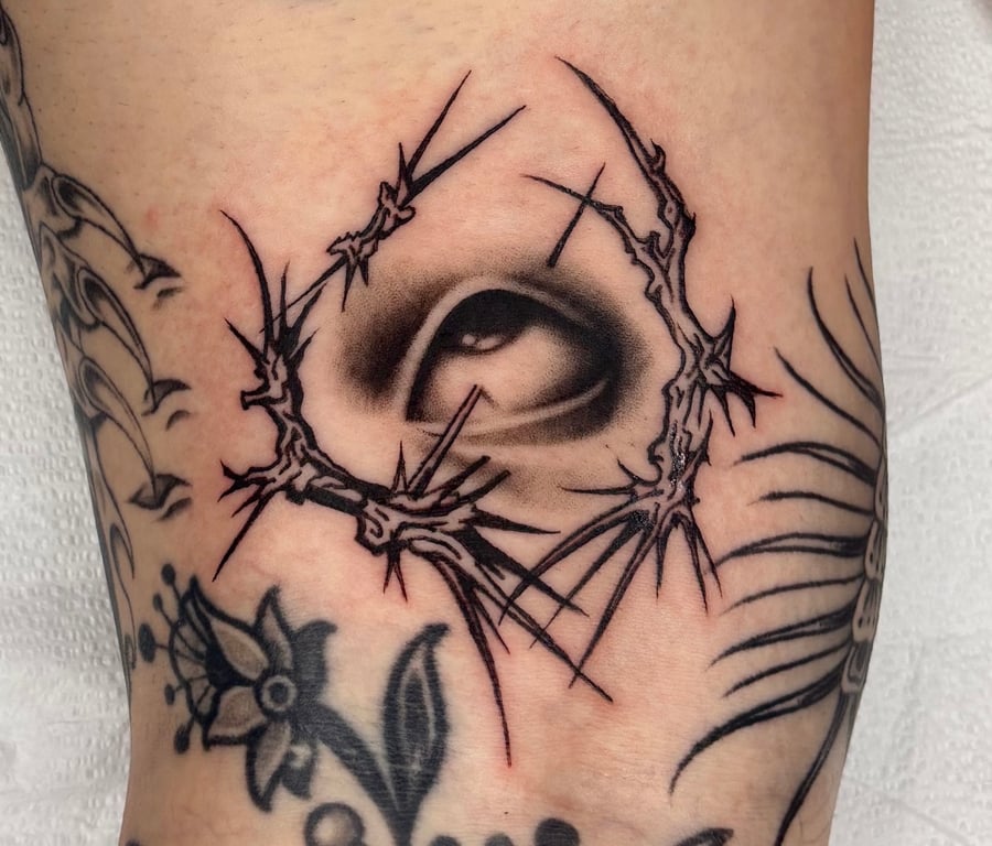 A black and grey tattoo of a realistic eye surrounded by abstract blackwork lines on the leg — by velvet devil, los angeles