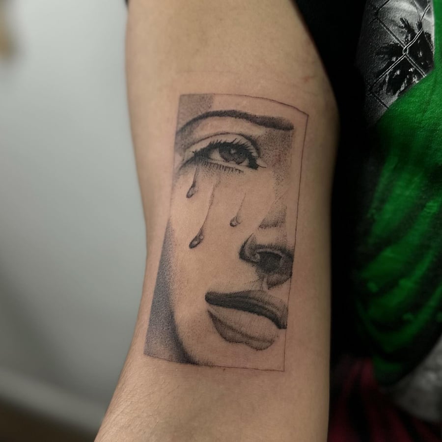 A black and grey Virgin Mary's face with tears on the upper arm, done in blackwork style — by Maddie Ramirez, los angeles