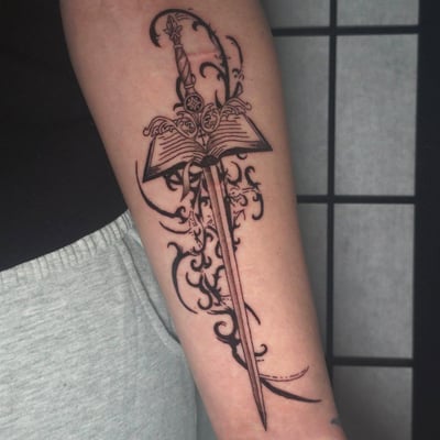 A bold blackwork tattoo of a sword with an open book on the forearm, featuring intricate illustrative details — by Miguel ANGELO, los angeles