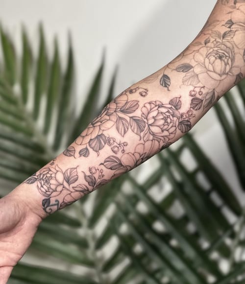 A delicate black and grey floral tattoo on the forearm featuring intricate flower designs — by Melanie Benoit, los angeles